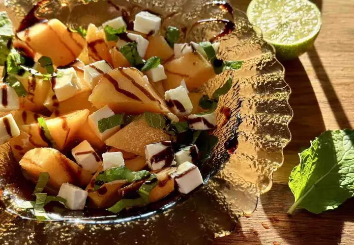 Sałatka z melona, sera feta, mięty i polewy balsamicznej w szklanej misie.