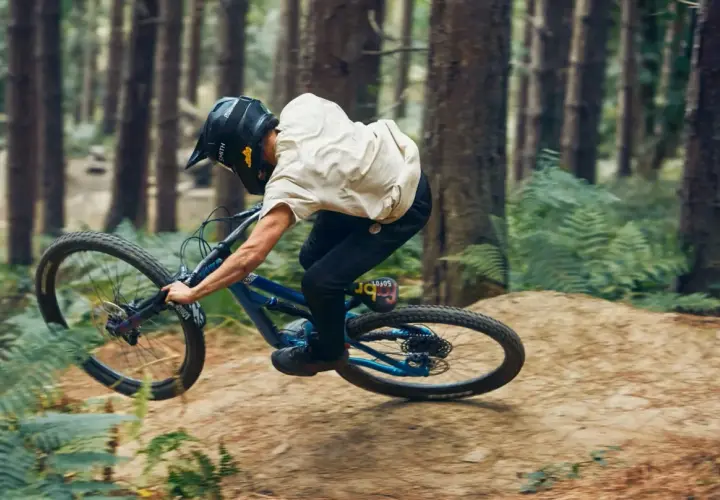 Rider in a forest, mid-air, demonstrating perfect mtb suspension tuning for a smooth landing.