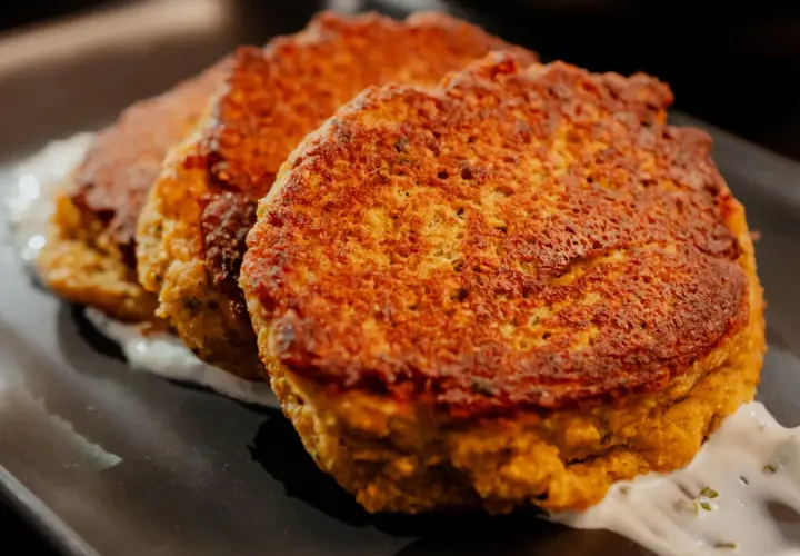 Trois galettes dorées de tortilla pois chiche, servies sur une sauce blanche crémeuse.