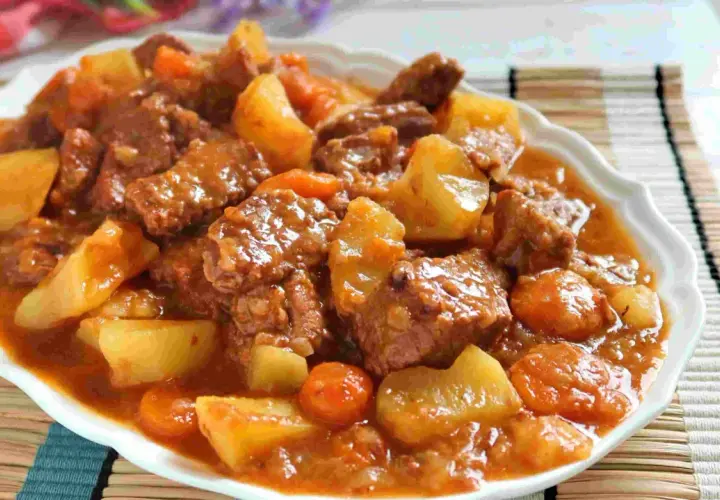 Un plato humeante de estofado de ternera con patatas y zanahorias en una salsa rica y sabrosa.