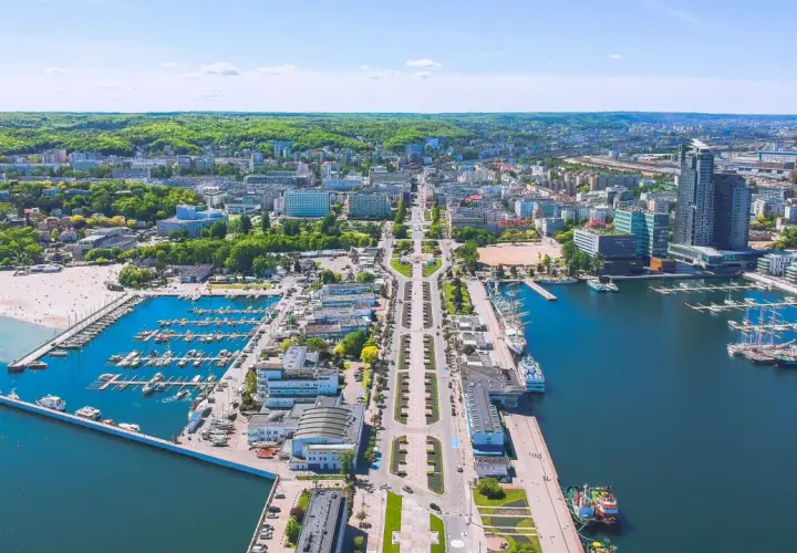 Gdynia o wszystkim: port jachtowy, plaża, nowoczesne budynki i zielone wzgórza. Widok z lotu ptaka na tętniące życiem miasto nad Bałtykiem.