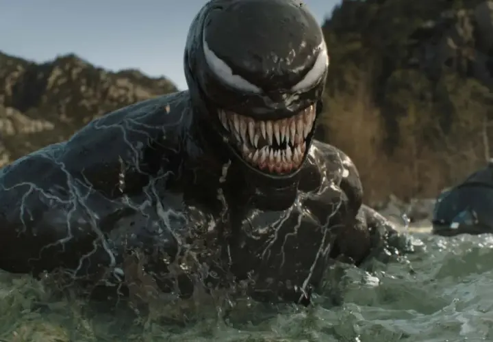 Venom émerge de l'eau, prêt pour la sortie de Venom 4. Le symbiote montre ses dents acérées dans un paysage rocheux.