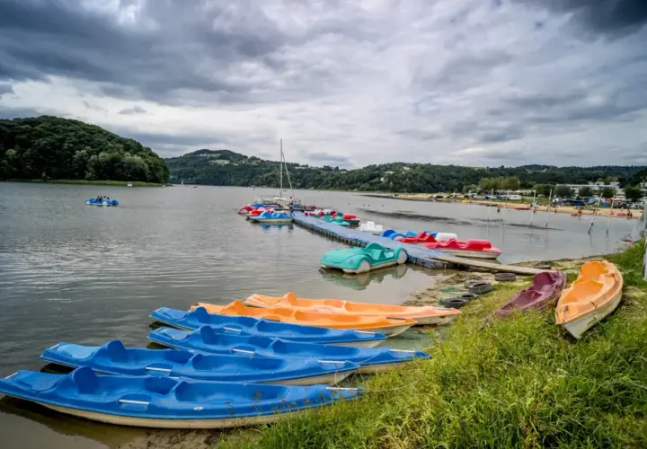 Jezioro Rożnowskie oferuje wiele atrakcji wodnych, w tym kolorowe rowerki wodne i kajaki czekające na plaży i przy pomoście.