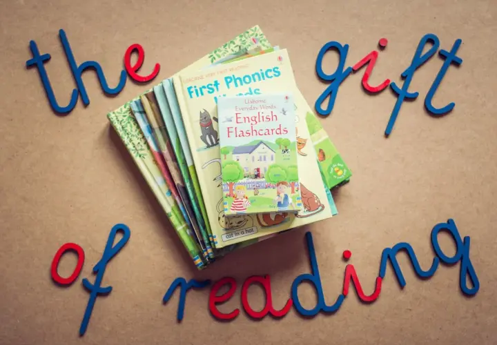 Proste książki po angielsku, idealne do nauki czytania. Stosik kolorowych książeczek i fiszek z napisami "the gift of reading".