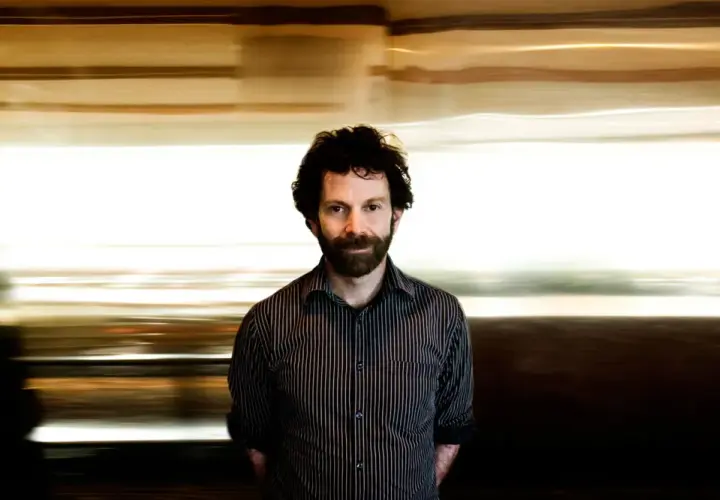 Charlie Kaufman, känd för sina unika filmer, med en drömsk, suddig bakgrund som speglar hans fantasifulla berättelser.