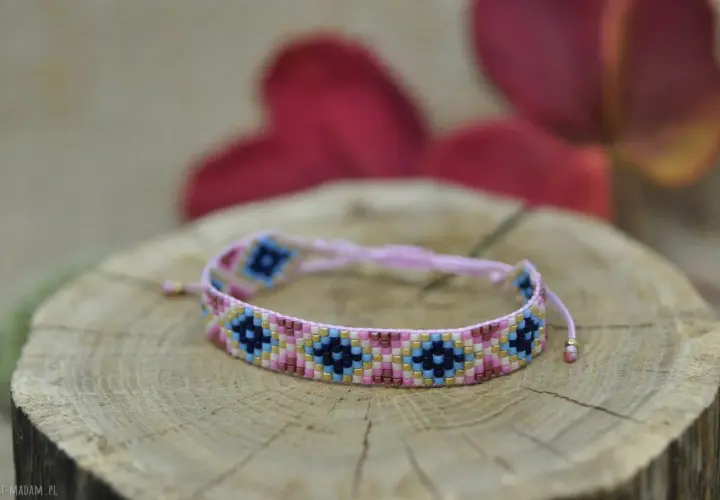 Kolorowa bransoletka z koralików diy, ozdobiona geometrycznym wzorem, spoczywa na drewnianym plastrze.