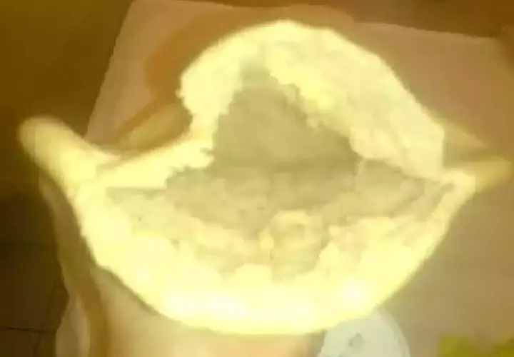 Une main tient un pain libanais ouvert, prêt à être garni. Sa texture moelleuse et sa poche invitent à la gourmandise.