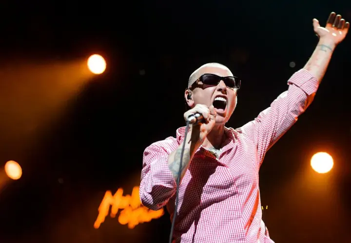 Sinéad O'Connor na koncercie, z ręką w górze, śpiewa swoje legendarne utwory.