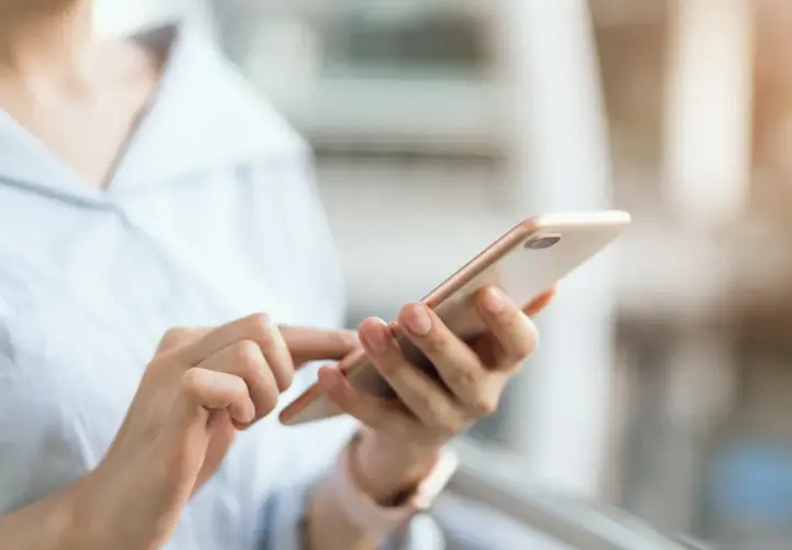Dłoń trzymająca telefon, szukająca instrukcji, jak wyłączyć tryb awaryjny w telefonie.