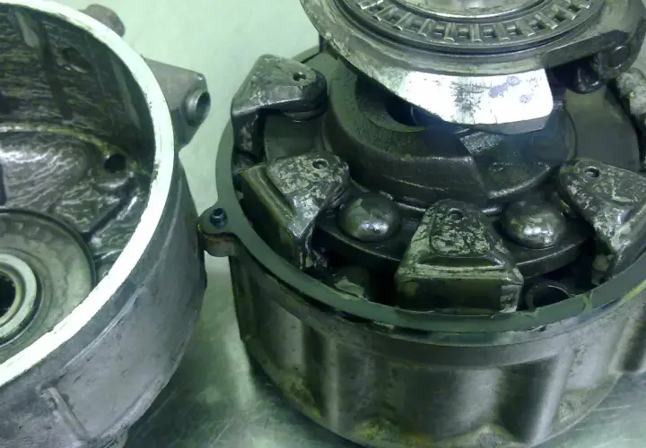 Rozłożone sprzęgło elektromagnetyczne klimatyzacji z widocznymi elementami mechanicznymi.