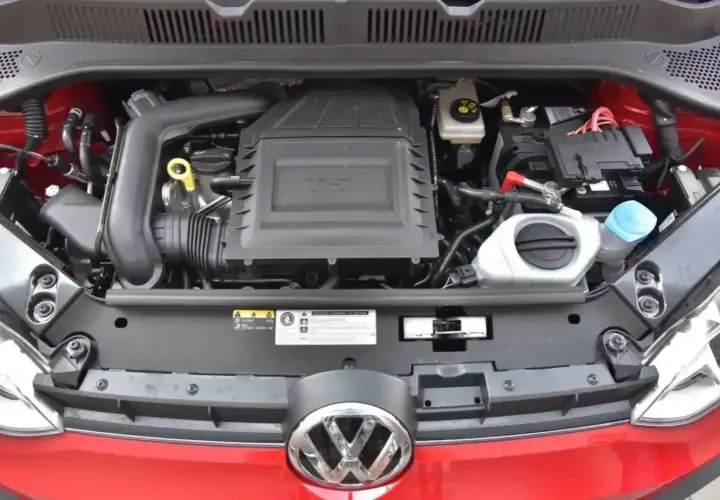 Silnik 1.0 TSI w czerwonym samochodzie Volkswagen. Widoczny akumulator, płyny i osłona silnika.
