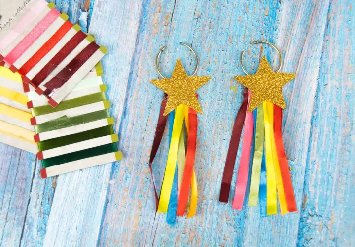 Aretes de carnaval manualidades con estrellas doradas y cintas de colores. Un conjunto de cintas de raso de varios tonos a la izquierda.