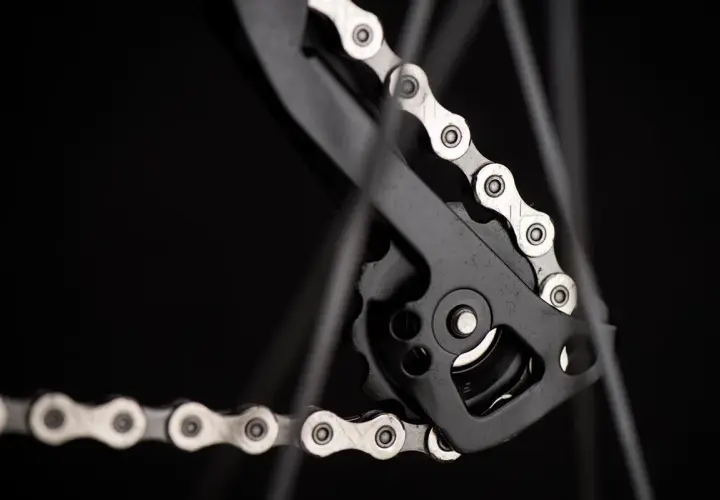 Zbliżenie na rowerowy napęd, gdzie widać mechanizm przerzutki i fragment łańcucha. Dowiedz się, jak liczyć ogniwa w łańcuchu, by zapewnić płynną jazdę.