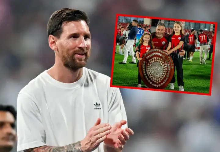 Lionel Messi, najbardziej utytułowany piłkarz w historii, uśmiecha się, podczas gdy w tle widać jego drużynę świętującą z pucharem.