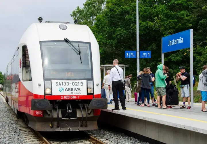 Pociąg Arriva z napisem "HEL" na stacji Jastarnia, gotowy do podróży z Gdańska na Hel. Ludzie czekają na peronie.