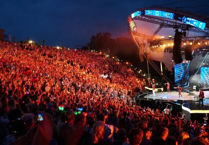 Tłumy rozbawionych ludzi na mrągowo festiwal, oświetlone sceną i kolorowymi światełkami.
