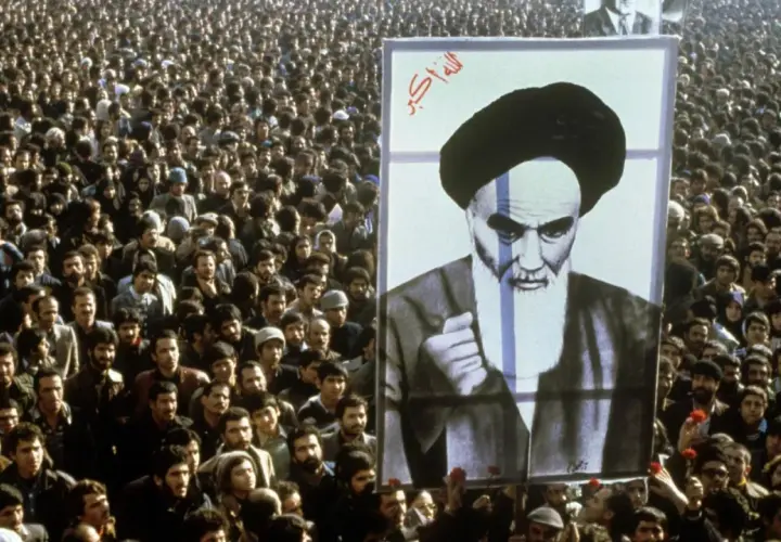 Massen jubeln bei der islamischen Revolution 1979 in Iran, ein riesiges Porträt von Ayatollah Khomeini wird hochgehalten.