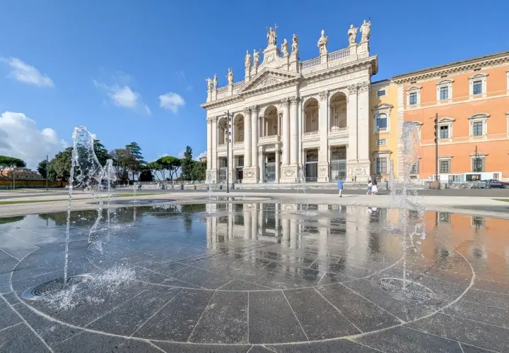 La fontaine devant la cathédrale de Rome, Saint-Jean-de-Latran, reflète le ciel bleu et l'architecture imposante.