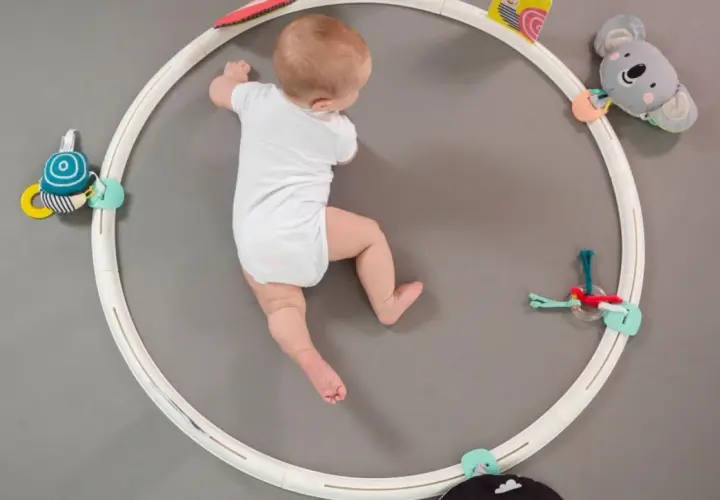 Neonato di 6 mesi esplora giochi appesi a un cerchio, stimolando i suoi primi esercizi e movimenti.