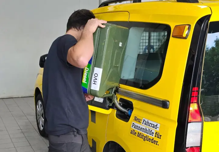 Uomo versa diesel paraffinico da tanica verde in un furgone giallo.