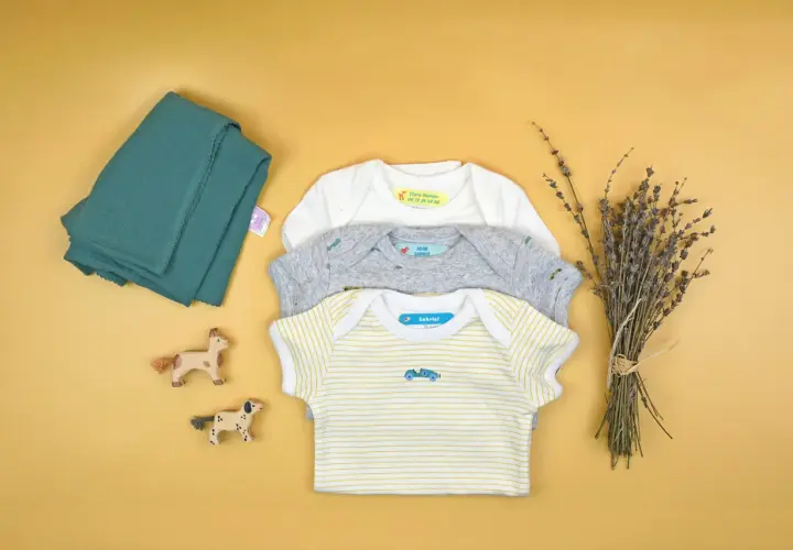 Trois bodies pour bébé avec des étiquettes personnalisées. Apprenez comment enlever une étiquette thermocollante pour réutiliser ces vêtements.
