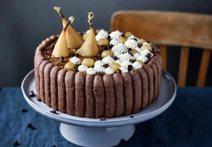 Charlotte poire chocolat, un gâteau élégant avec des poires pochées dorées, de la crème fouettée et des éclats de chocolat.