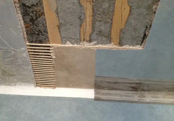 Soffitto in fase di ristrutturazione, con travi a vista e intonaco parzialmente rimosso. Si vede come rasare un soffitto rovinato, con listelli di legno e nuovo intonaco.