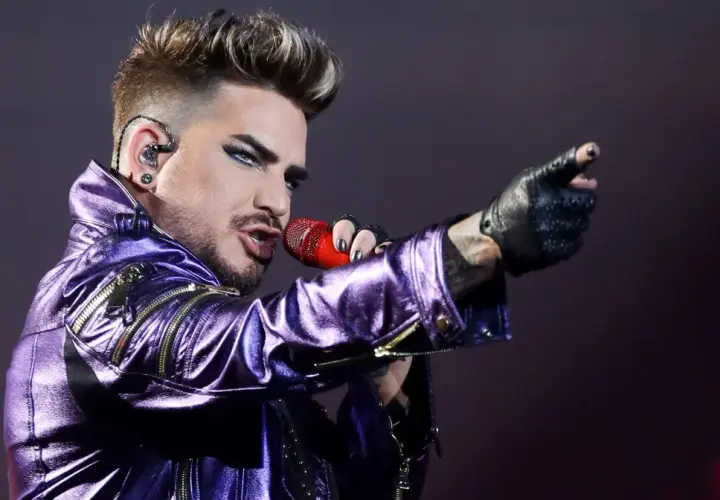 Adam Lambert w błyszczącej, fioletowej kurtce śpiewa z mikrofonem, wskazując palcem. To jakby Queen powrócił na scenę z nową energią.