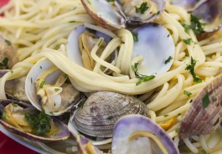 Un piatto invitante di spaghetti alle vongole, con pasta dorata e molluschi freschi, guarnito con prezzemolo tritato.