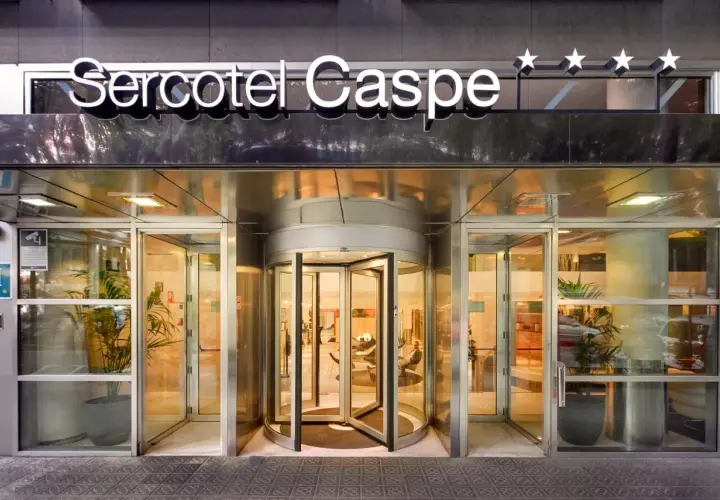 Entrada principal del Sercotel Caspe, con puerta giratoria y letrero luminoso.