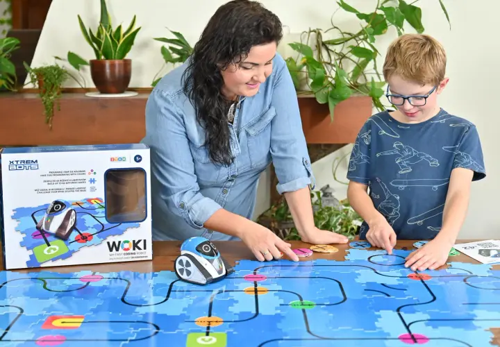Mama i syn bawią się robotem WOKI, ucząc się kodowania dla 6 latka. Kolorowe klocki tworzą labirynt.