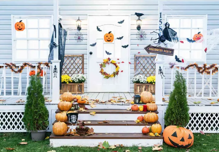 Porche decorado para Halloween con calabazas, telarañas, murciélagos y un esqueleto.