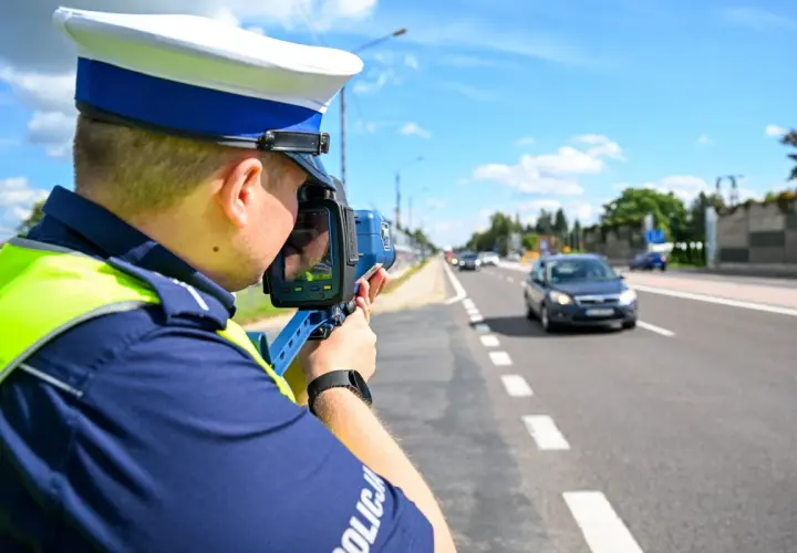 Policjant mierzy prędkość pojazdu, aby ustalić taryfikator punktów karnych.