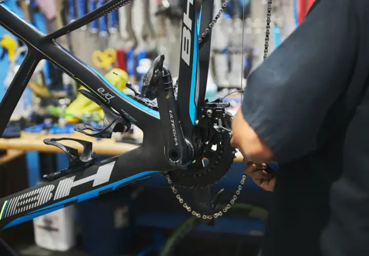 Mechanik dokonuje regulacji przedniej przerzutki w rowerze szosowym. Widać korbę Ultegra i ramę BH.