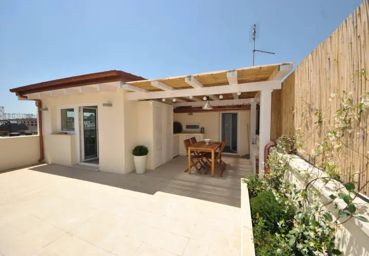 Un terrazzo sul tetto con tavolo in legno, pergola di bambù e vista sulla città. Ideale per cene all'aperto.