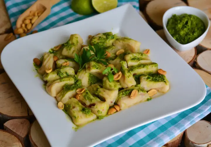 Pyszne gnocchi z pesto, posypane orzeszkami ziemnymi i udekorowane natką pietruszki. Idealne danie dla miłośników włoskich smaków.