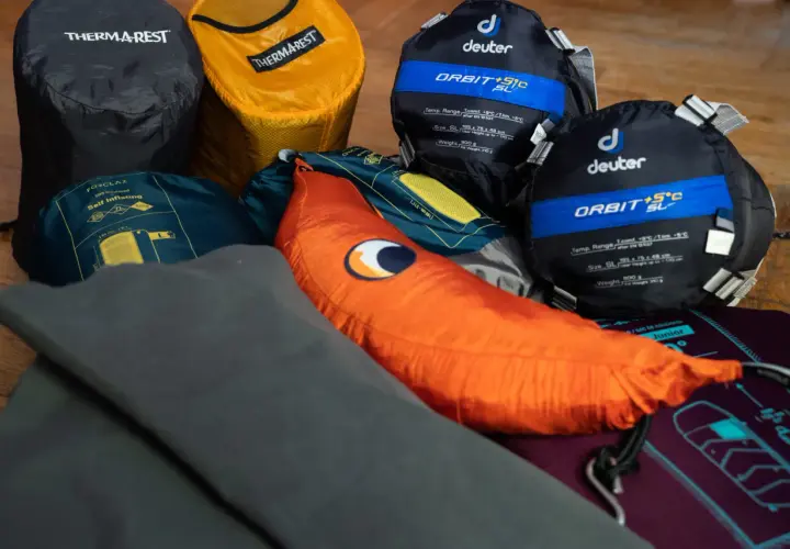 Śpiwory Deuter, karimata Thermarest i pomarańczowa poduszka – to wszystko, co zabrać pod namiot na nocleg w plenerze.