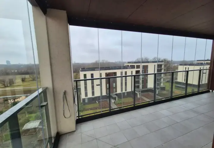 Szklane balustrady i zadaszenie to świetny sposób, jak osłonić balkon przed wiatrem i deszczem, zapewniając komfortowy widok na nowoczesne budynki.