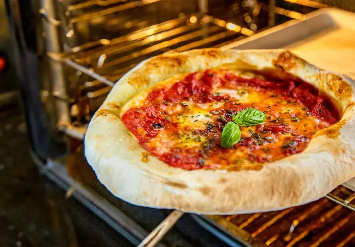 Heißer Pizzaofen: Eine Margherita-Pizza mit frischem Basilikum wird bei optimaler Pizzaofen Temperatur gebacken.
