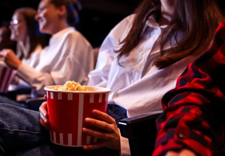 Ludzie w kinie jedzą popcorn. Zastanawiasz się, ile kosztują nachosy w kinie?