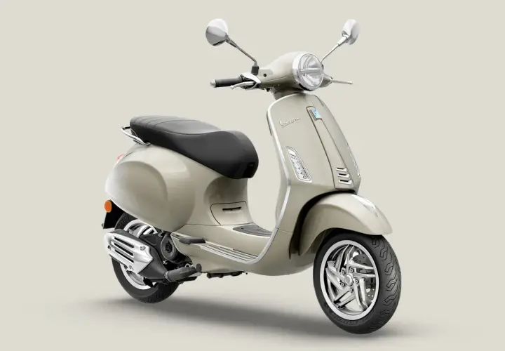 Vespa Primavera 50 color arena, con asiento negro y detalles cromados. Ideal para paseos urbanos.