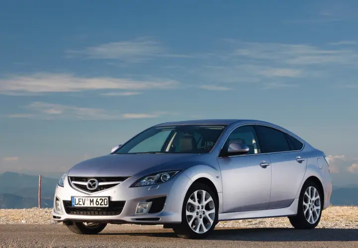 Srebrna Mazda 6 2.0 benzyna na tle błękitnego nieba i gór.