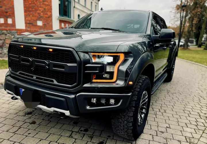 Mroczny Ford F-150 Raptor z pomarańczowymi światłami dziennymi, gotowy na przygodę.