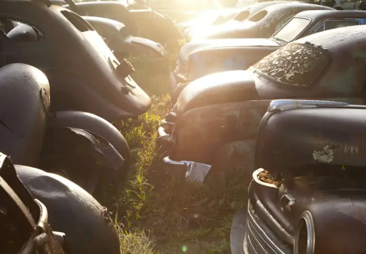 Rottami d'auto d'epoca al tramonto. Chissà quanto costa rottamare un'auto così, tra ruggine e ricordi.