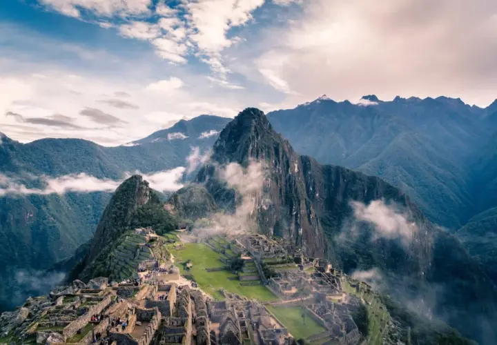 Die Ruinen von Machu Picchu, eingebettet in nebelverhangene Andengipfel. Ein atemberaubender Blick auf die Inka-Stadt, die sich an die Berghänge schmiegt.