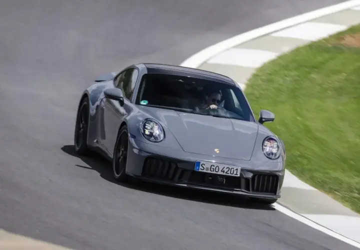 Un'auto sportiva ibrida grigia sfreccia su una pista, con il guidatore concentrato.