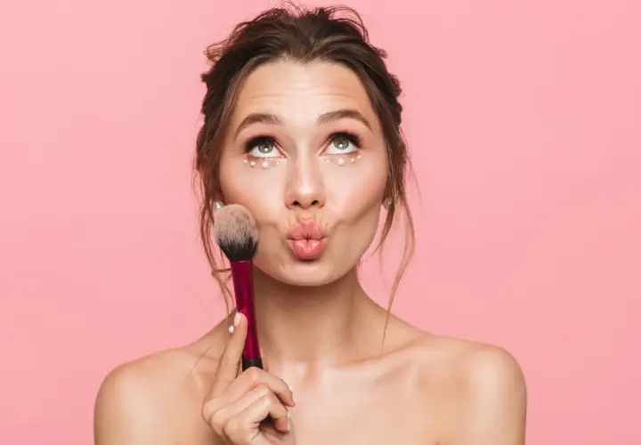 Jeune fille avec un maquillage simple et des perles sous les yeux, tenant un pinceau. Idéal pour un maquillage simple pour jeune fille.