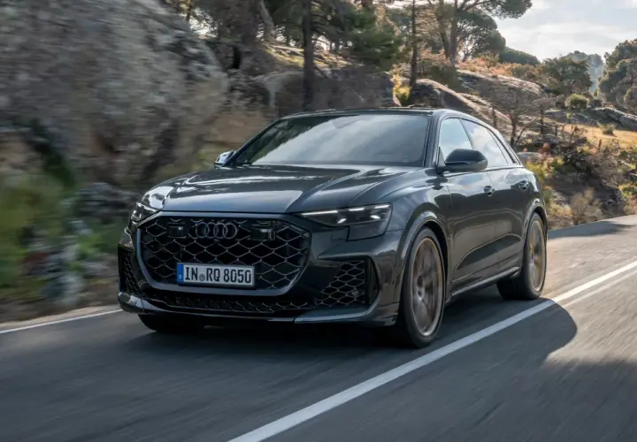 Czarny Audi RS Q8 pędzi po krętej drodze wśród skał i drzew. Sprawdź aktualną audi rsq8 cena!
