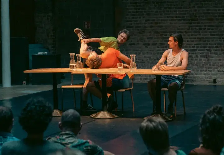 Akrobater på en scen vid ett bord, en del av föreställningen på Stockholm Fringe Festival.