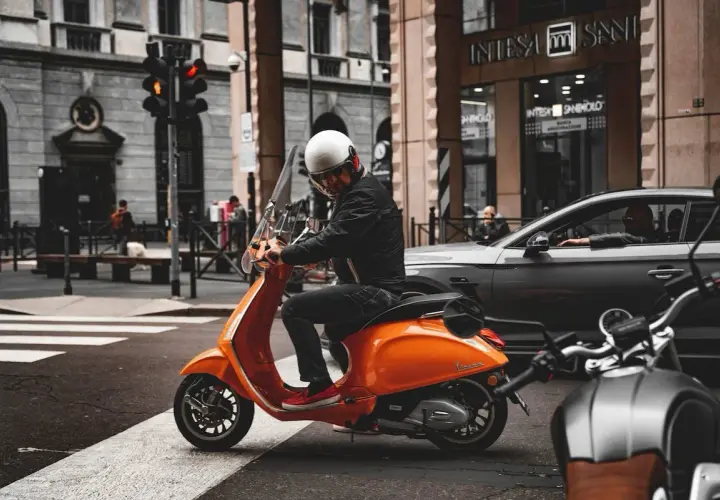 Uomo su scooter 150 con patente B, fermo al semaforo in città.